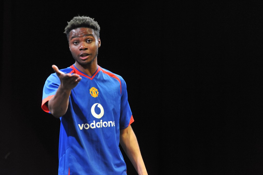 A young man gestures towards the camera